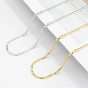 Minimalist gold and silver stainless steel snake bone chain necklaces on a white block