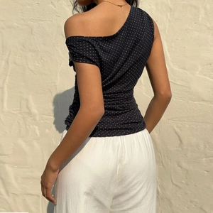 Détail du haut sexy à pois noirs à une épaule avec strass et vue de l'arrière