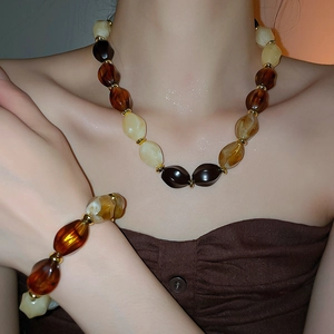 Close-up of vintage amber and beige acrylic beaded necklace set with golden spacers