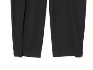 Detailed macro view of black pleated trouser cuffs featuring fine plain weave fabric
