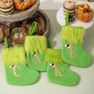 Detailed view of green knitted Christmas stockings with gold glitter letters and fur trim