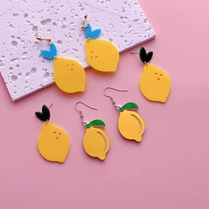 Bright yellow acrylic lemon drop earrings with blue and green leaves on pink background