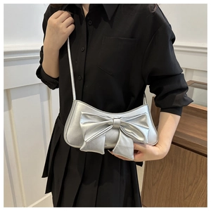 Metallic silver bow shoulder bag in textured PU leather worn by a model in black outfit