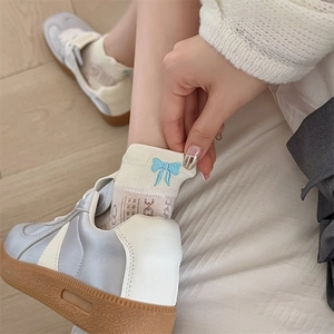 Detail of white mesh socks with blue bow embroidery and ribbed cuff design