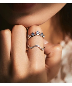 Close-up of S925 silver crown ring with blue gems and wave band on finger