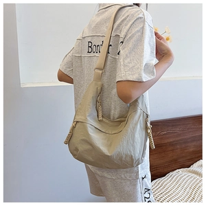 Dettaglio della tracolla regolabile e della zip intrecciata su borsa in nylon beige