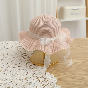 Detailed straw weave of pink sun hat with organza bow and pearl accent on display stand