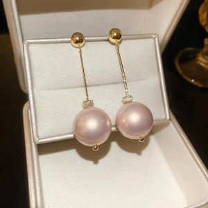 Detailed macro view of long 18k gold-plated floral earrings with lavender pearls and crystals