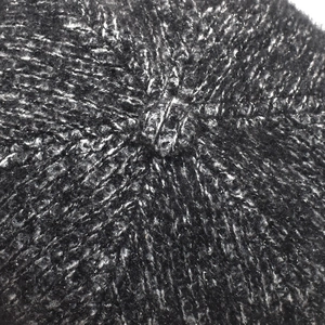Close-up of thick black and white tweed knit texture on the top of the warm winter cap