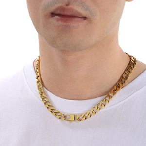 Close-up of a thick gold Cuban link chain necklace with a box clasp worn by a male model
