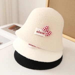Detailed pile of plush bucket hats in beige, white, and black with bow accents