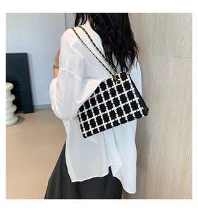 Close-up of a black and white houndstooth tweed shoulder bag with gold chain strap