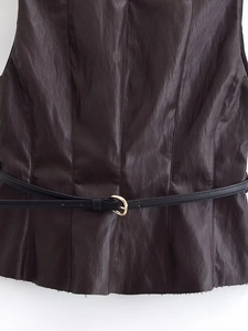 Détail d'un haut en similicuir marron foncé avec ceinture noire et boucle dorée