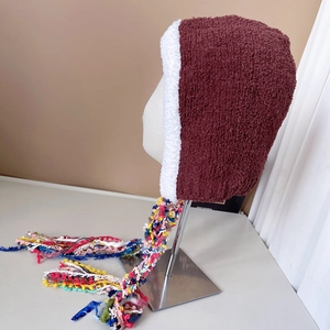 Detailed close-up of dark red knitted ear protection hat with colorful long tassels
