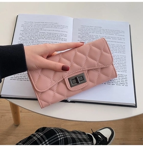 Detailed shot of a mauve quilted leather long wallet held over an open vintage book
