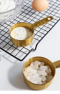 Macro shot of 1/3 CUP 80ml golden stainless steel measuring cups with sugar and flour