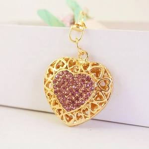 Golden heart keychain with pink rhinestones and hollow floral patterns on white box