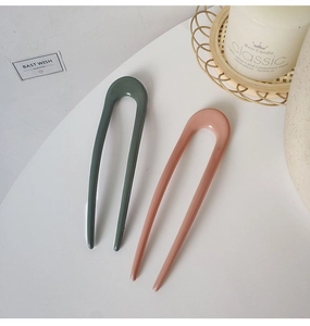 Detail of dark green and dusty pink U-shaped hair pins with smooth glazed finish