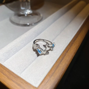 Close-up of silver ring with light blue zircon butterfly and star design on a jewelry tray
