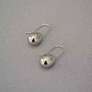 Macro view of silver water drop earrings with polished metallic mirror finish texture