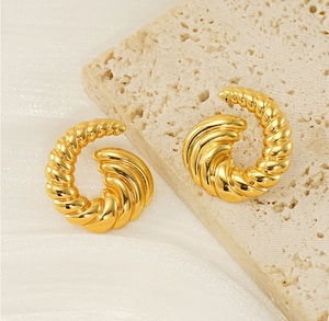 Macro detail of 18k gold plated spiral hoop earrings on a neutral stone background