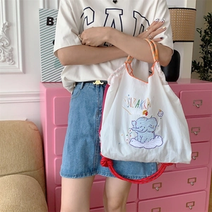 Close-up of cute elephant embroidery on a white nylon tote bag with drawstring details