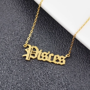 Macro shot of gold Pisces pendant necklace on a textured black and white background