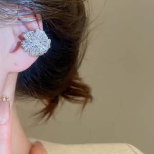 Detailed close-up of a silver petal-shaped ear cuff with sparkling zircon crystals