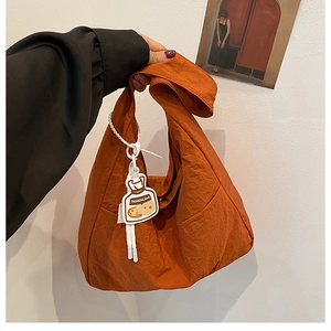 Detail of caramel nylon tote bag featuring pleated texture and round fashion tag