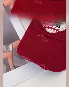 Detail of distressed burgundy canvas baseball cap featuring vintage heart embroidery