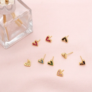 Detailed view of colorful mini zircon heart stud earrings on a soft pink fabric