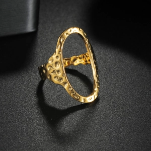 Detailed macro view of gold-plated titanium ring with hammered texture and hollow oval design