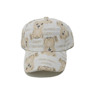 Detail of light beige baseball cap with Happy Little Bear pattern and canvas texture