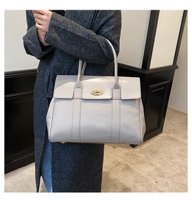 Detail of grey leather tote bag featuring a gold twist lock and dual top handles