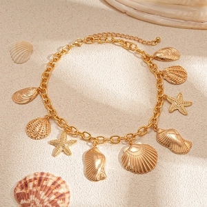 Detail of a golden starfish and seashell pendant necklace on a sandy texture background