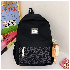 Close-up of black canvas school bag with cat print, white logo and plush bread charm
