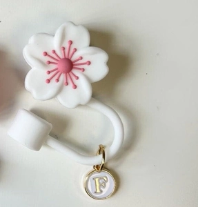 Macro detail of white cherry blossom straw cover with letter F charm for tumbler