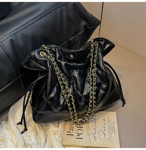 Detail view of black quilted PU leather bucket bag with gold chain and drawstring design