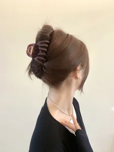 Close-up of a large amber hair claw clip styled on a model wearing a pearl necklace