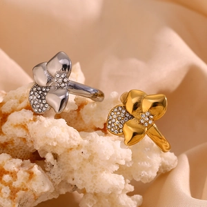 Detail of 18K gold plated flower rings with crystals on white coral stone display