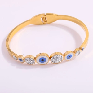 Detail view of gold-plated evil eye hinge bracelet with blue enamel and clear crystals