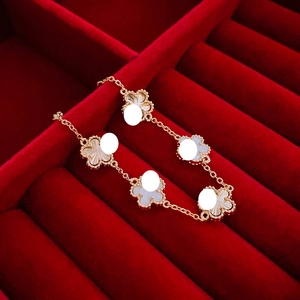 Detail of five-flower clover bracelet with white mother-of-pearl and sunburst gold texture