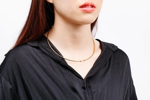 Close-up of minimalist gold stainless steel collar necklace with two bead accents on model
