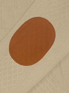 Dettaglio del tessuto a maglia kaki con toppa marrone sul gomito e cuciture rifinite