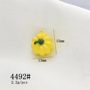 Detail view of a 13x15mm yellow pumpkin alloy pendant with green stem for DIY jewelry