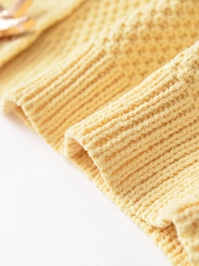 Macro view of light yellow knitted cardigan with vertical ribbed texture and fine stitching