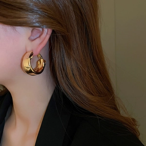Close-up of gold double-layer cross hoop earrings with a high-polished mirror finish