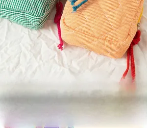 Detailed view of quilted cotton cosmetic bags with green plaid and orange stripes designs