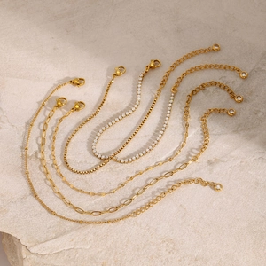 Detailed close-up of multiple gold-plated bracelets featuring cuboid and tennis zircon links