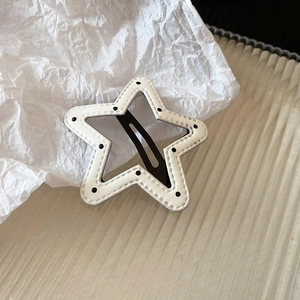 Close-up of star-shaped white leather hair clip with black polka dots and fine stitching